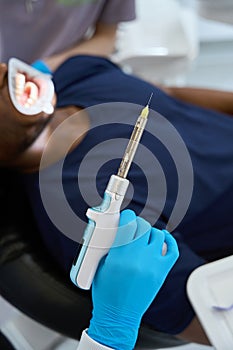 Woman dentist holding electric local anesthesia injector