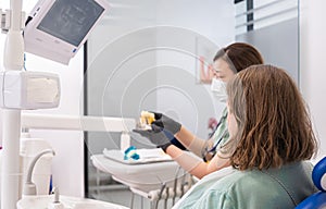 Woman dentist and patient reviewing digital X-ray on screen at modern clinic