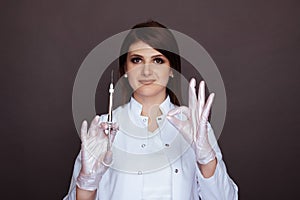 Woman dentist showing ok sign and holding syringe with anaesthesia isolated.