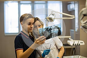 Woman dentist showing to patient x-ray the jaw at clinic