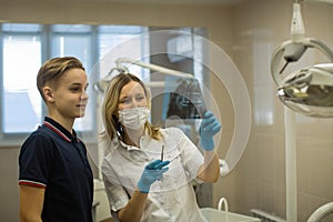 Woman dentist showing to patient x-ray the jaw at medical clinic.