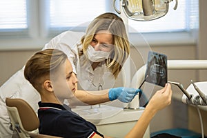 Woman dentist showing to patient x-ray the jaw at medical clinic.