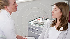Woman dentist talking with female patient in clinic. Female professional doctor at work. Dental check up