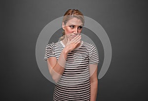 A woman depicts the contempt of gossip or discontent against a gray background.