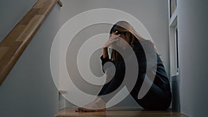 Woman with depression sitting alone on the stairs  in the dark room.