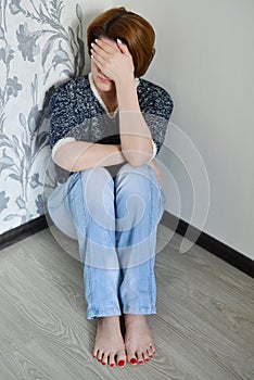 Woman with depression sitting in the corner of room