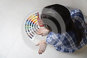 A woman designer choosing an interior colour using the color palette, while sitting on the floor.