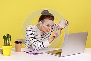 Woman designer or photographer making photo frame with hands and focusing at laptop screen.