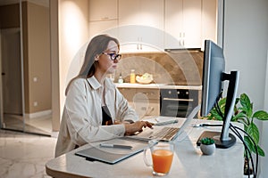 Woman designer working at home office on new ideas. Young happy female freelancer working on project, watching movie on computer,