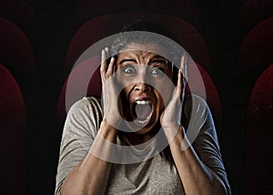 Woman desperate and scared terrorized at cinema hall watching horror movie