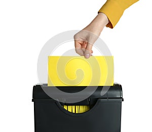 Woman destroying sheet of yellow paper with shredder on white background, closeup