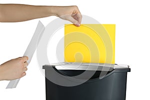Woman destroying sheet of yellow paper with shredder on white background, closeup