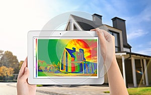 Woman detecting heat loss in house using thermal viewer on tablet. Energy efficiency