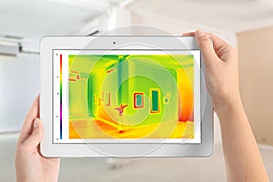 Woman detecting heat loss in room using thermal viewer. Energy efficiency