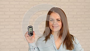 Woman with diabetes holds a glucometer with a good level of glucose in the blood