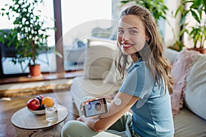 Woman with diabetes using continuous glucose monitor. Diabetic woman connecting CGM to smartphone to monitor her blood