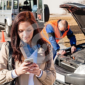 Woman dialing on cellphone after car breakdown