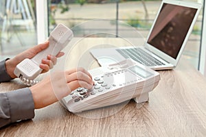 Woman dialing number on telephone