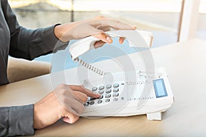 Woman dialing number on telephone