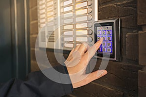 Woman dialing passcode on intercom security keypad