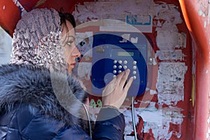 Woman dialling on a public telephone photo