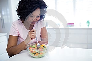 Woman on diet eating salad in kitchen