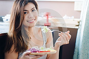 Woman dieting and control calories for good health concept. Happy dieting woman sitting on the floor and eating salad.