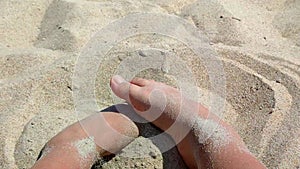 Woman digging with feet in the sand. Person playing burying his feet in dry sand
