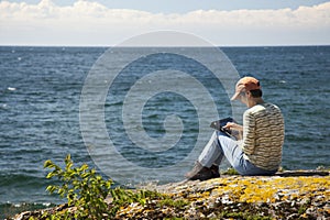 Woman with digital tablet sitting by the lake