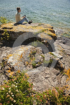 Woman with digital tablet sitting by the lake