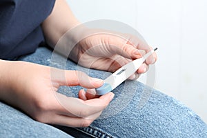 Woman with digital thermometer on background, closeup