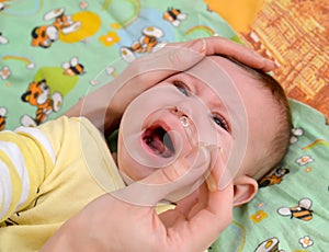 The woman digs in drops in a nose to the sick crying baby