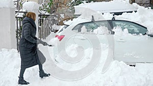 woman digs up a car buried under the snow with a shovel