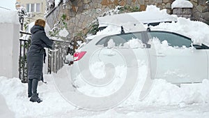 woman digs up a car buried under the snow with a shovel