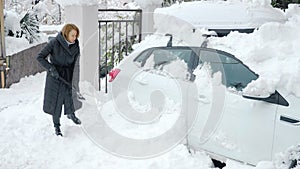 woman digs up a car buried under the snow with a shovel