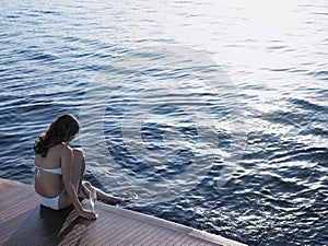 Woman Dipping Foot In Sea While Sitting On Yacht's Floorboard