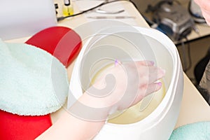 Woman Dipping Hand in Spa Parrafin Wax Treatment