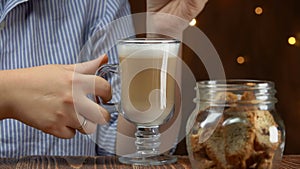 Woman dips cantucci coockies in latte coffee