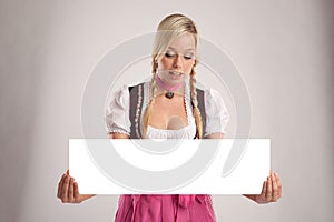 Woman with dirndl holds an empty signboard