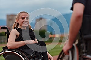 A woman with disability in a wheelchair talking with friend after training on the marathon course