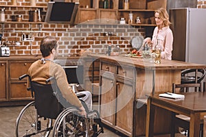 woman with disabled man in wheelchair cooking dinner together at home