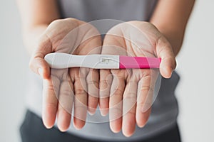 woman discovering and showing her positive pregnancy test on hand