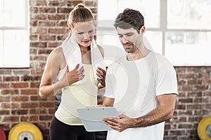 Woman discussing her performance on clipboard with trainer