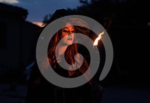 Woman disguised as a witch holding a flaming torch