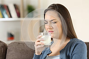 Woman disgusted tasing milk with bad flavor photo