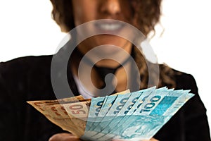 Woman displaying a spread of cash from Brazil. Financial, payment and loan concept