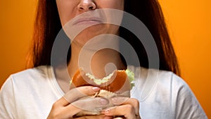 Woman dissatisfied with unappetizing hamburger, low food quality, closeup
