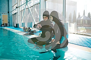 Woman and divemaster in scuba gear, diving school