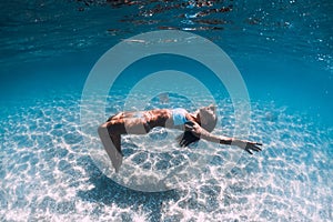 Woman diver glides over sandy sea. Freediving in blue sea