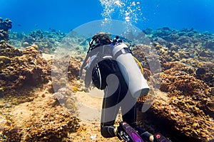 Woman diver at tropical coral reef scuba diving in tropical ocean photo